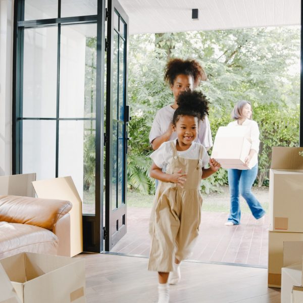 Happy African American young family bought new house. Mom, Dad, Happy African American young family bought new house. Mom, Dad, and child happy hold cardboard boxes for move object and having fun laugh into modern home. New real estate dwelling, loan and mortgage.