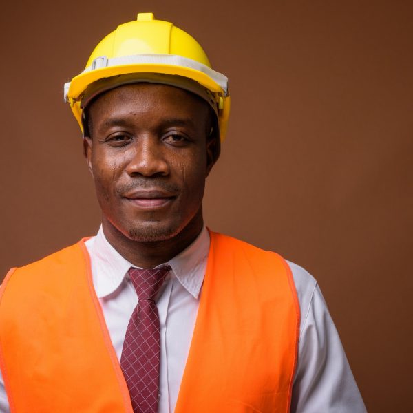Young African man construction worker against brown background Young African man construction worker against brown background